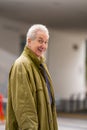 Old man posing in a green oversize trenchcoat