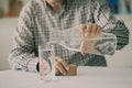 Old man pouring water from bottle to glass in kitchen Royalty Free Stock Photo