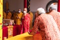 An Old man prepared the offerings tray on the top of an orange table for the monks