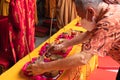 An Old man prepared the offerings tray on the top of an orange table for the monks