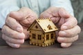 Old man protecting house model with hands.Risk insurance.The con Royalty Free Stock Photo