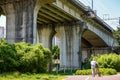 An old man pushes a bicycle and walks under a large railway bridge Royalty Free Stock Photo