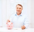 Old man putting coin into big piggy bank Royalty Free Stock Photo