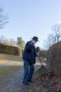 Old man raking fallen leaves in the garden, senior man gardening