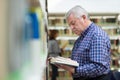 Old man reading and choosing book in library Royalty Free Stock Photo