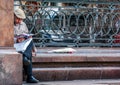 An old man reading news paper by the monument to Peter Tchaikovsky. Tourists walking around Moscow.