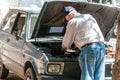 Old man repairs his broken Yugo car on the street