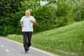 Old man running on modern city park`s racetrack. Royalty Free Stock Photo