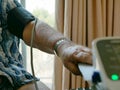 An old man`s arm with a pressure cuff on checking his blood pressure at home by himself Royalty Free Stock Photo