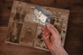 Old manÃ¢â¬â¢s male hands hold old retro family photos over an album with vintage monochrome photographs in sepia color, the concept