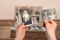 Old manÃ¢â¬â¢s male hands hold old retro family photos over an album with vintage monochrome photographs in sepia color, genealogy