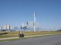 Old man in scoot mobile passes industrial buildings of eemshaven on sunny summer day Royalty Free Stock Photo