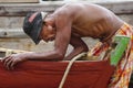 An old man is servicing a broken boat.