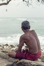 Old man sittiing on a rock watching the sea Royalty Free Stock Photo