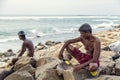 Old man sittiing on a rock with a young man watching the sea Royalty Free Stock Photo