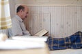 Old man sitting at home reading book in armchair. Royalty Free Stock Photo