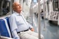 Old man sitting inside subway train