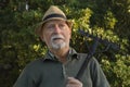 Old man sitting with rake in a wood