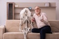 Old man sitting on the sofa with the female skeleton