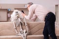 Old man sitting on the sofa with the female skeleton