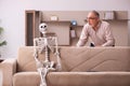 Old man sitting on the sofa with the female skeleton