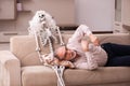 Old man sitting on the sofa with the female skeleton