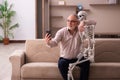 Old man sitting on the sofa with the female skeleton Royalty Free Stock Photo