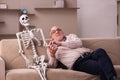 Old man sitting on the sofa with the female skeleton