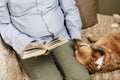 Old man sitting on the sofa with his lovely dog and book Royalty Free Stock Photo