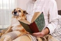 Old man sitting on the sofa with his lovely dog and book Royalty Free Stock Photo