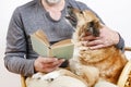 Old man sitting on the sofa with his lovely dog and book Royalty Free Stock Photo