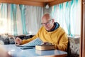 Old man sitting at table in recreational vehicle and solving crossword