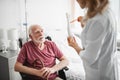 Old man sitting in wheelchair and listening doctor