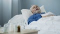 Old man sleeping in bed at hospital ward, antibiotics standing on the table Royalty Free Stock Photo
