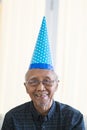 Old man smiling at camera with birthday hat Royalty Free Stock Photo