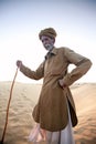 An old man standing on a dune, living in the desert, a camel driver