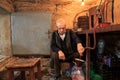 The old man stands in the old wine cellar and boasts wine in bot Royalty Free Stock Photo