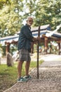 An old man with a stick and a backache is walking in the park. Hike in the 60s Royalty Free Stock Photo