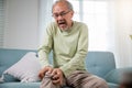 Old man suffering from knee joint pain on sofa living room Royalty Free Stock Photo