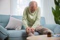 Old man suffering from knee joint pain on sofa living room Royalty Free Stock Photo