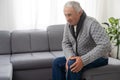 Old man suffering from knee pain sitting sofa Royalty Free Stock Photo