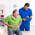 Old man visiting young male doctor gastroenterologist