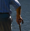 Old man walking with his hands on a wooden walking stick Royalty Free Stock Photo