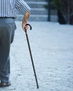 Old man walking with his hands on a wooden walking stick Royalty Free Stock Photo