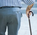 Old man walking with his hands on a wooden walking stick Royalty Free Stock Photo