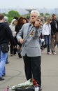 Old man wearing Soviet orders and medals on his costume playing violin, celebration of the Victory Day