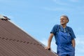 Old man working, building a roof of a house without any safety devices, wearing work clothes, blue overall, on a warm sunny day, d Royalty Free Stock Photo