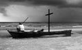Old man on wreck boat with wooden cross look at the ocean