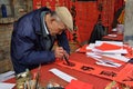 FOSHAN, CHINA - CIRCA JANUARY 2018: An old man writing blessing antithetical couples during the Spring Festival. Royalty Free Stock Photo