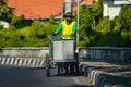 An old man in yellow clothes pushes an iron cart along the side of a highway in Indonesia